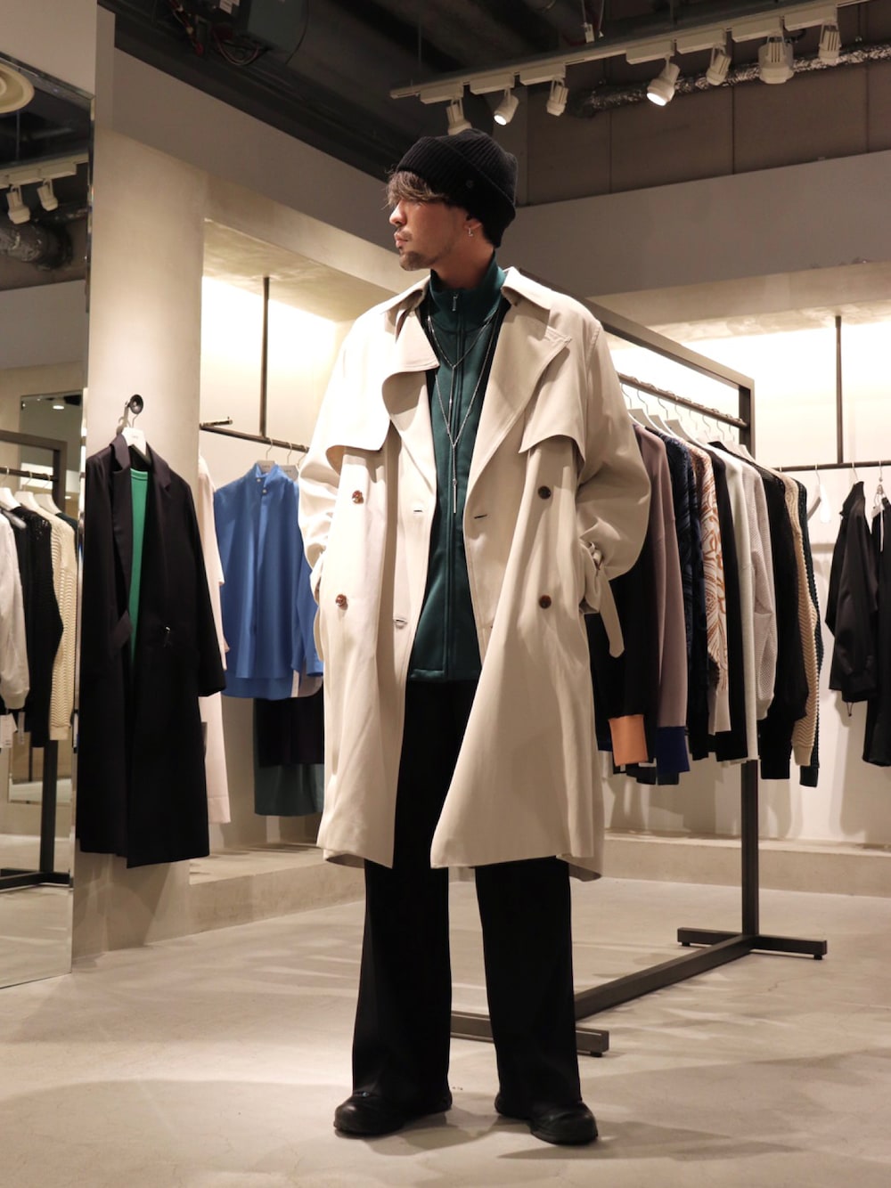 ベージュ系のトレンチコート、ブラック系のスラックス、グリーン系のブルゾンを着用したメンズの冬コーディネートの1枚目の写真