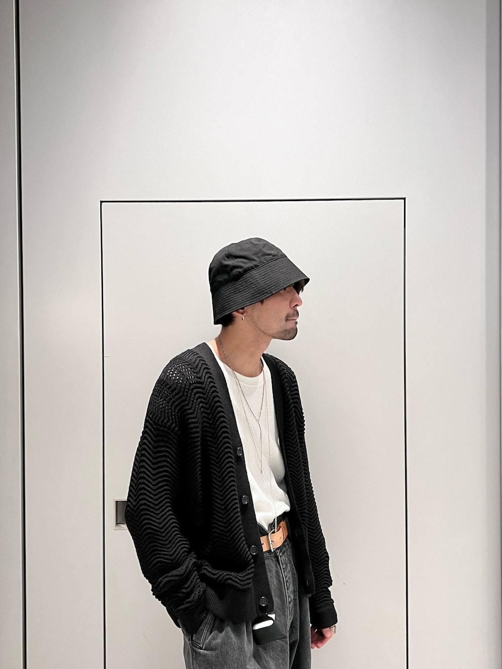 ブラック系のニット/セーター、グレー系のパンツ、ブラック系のハットを着用したメンズの春コーディネートの2枚目の写真