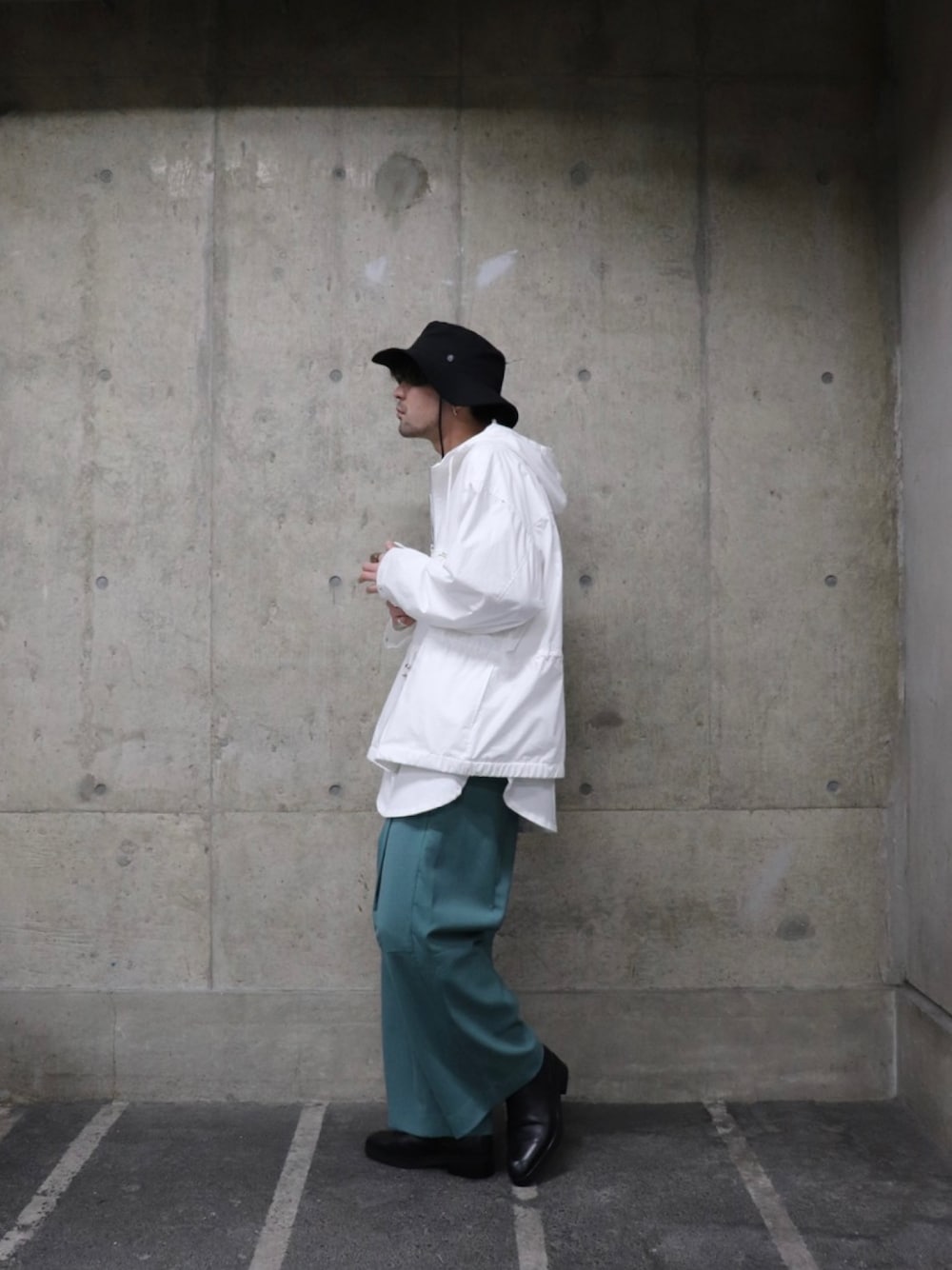 ホワイト系のマウンテンパーカー、ホワイト系のTシャツ/カットソー、グリーン系のパンツを着用したメンズの春コーディネートの2枚目の写真