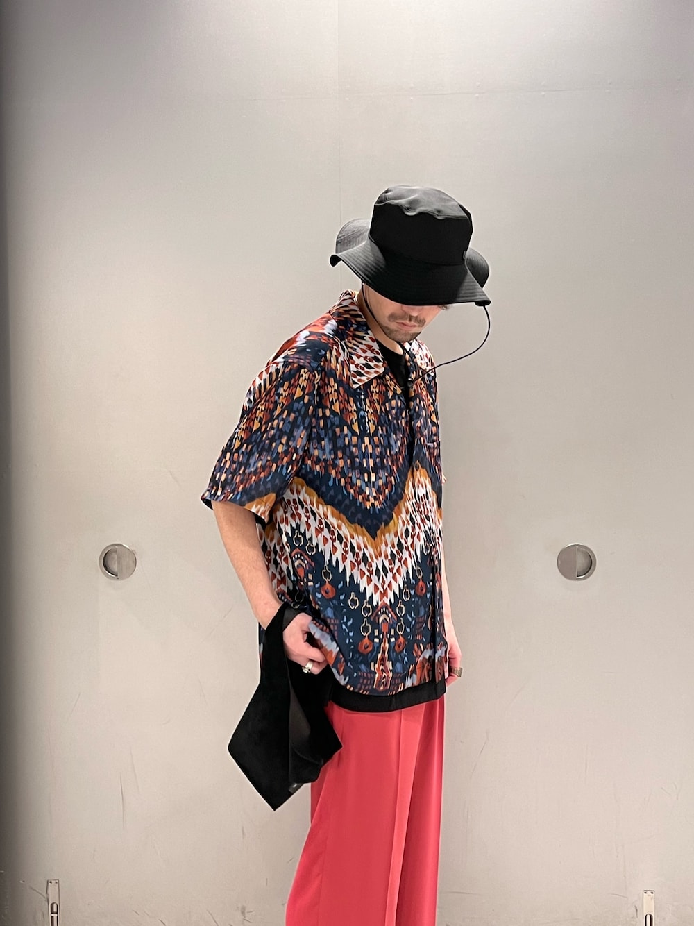 ブルー系のシャツ/ブラウス、ブラック系のトートバッグ、ピンク系のスラックスを着用したメンズの春コーディネートの2枚目の写真