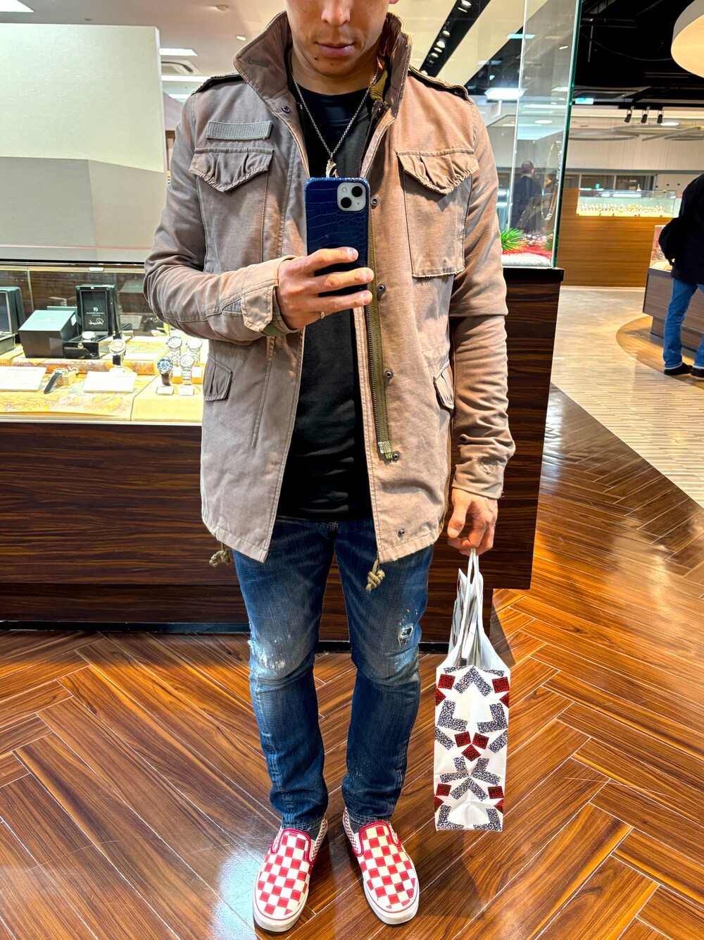 グリーン系のミリタリージャケット、ブルー系のデニムパンツ、レッド系のスリッポンを着用したメンズの冬コーディネートの1枚目の写真