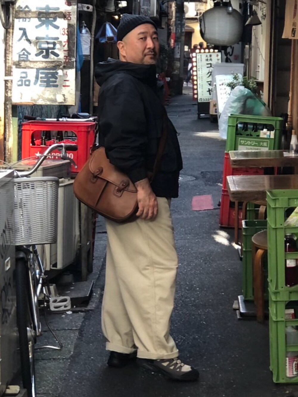 ベージュ系のスニーカー、ベージュ系のパンツ、ブラック系のパーカーを着用したメンズの秋コーディネートの1枚目の写真