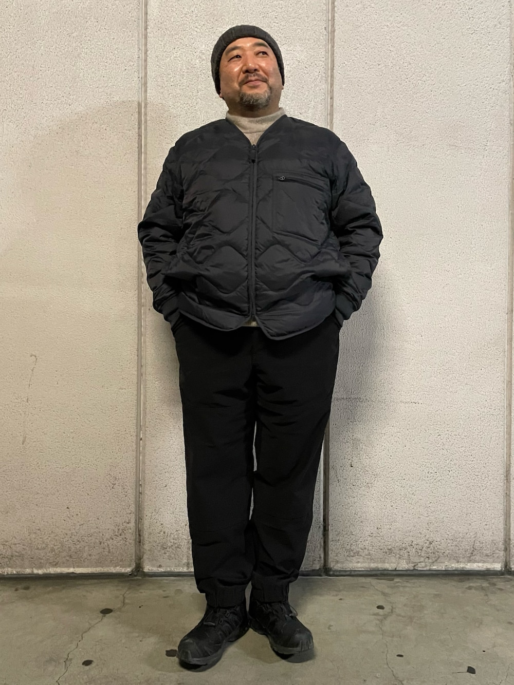 ブラック系のダウンジャケット/コート、ベージュ系のニット/セーター、ブラック系のスニーカーを着用したメンズの冬コーディネートの1枚目の写真