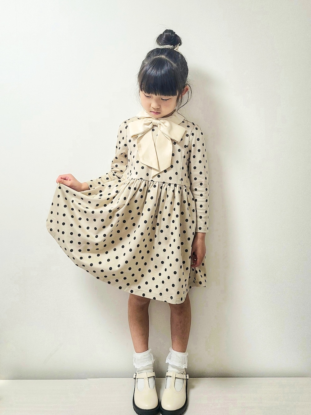 ベージュ系のワンピース、ホワイト系のシューズ、パープル系のランドセルを着用したキッズの春コーディネートの2枚目の写真