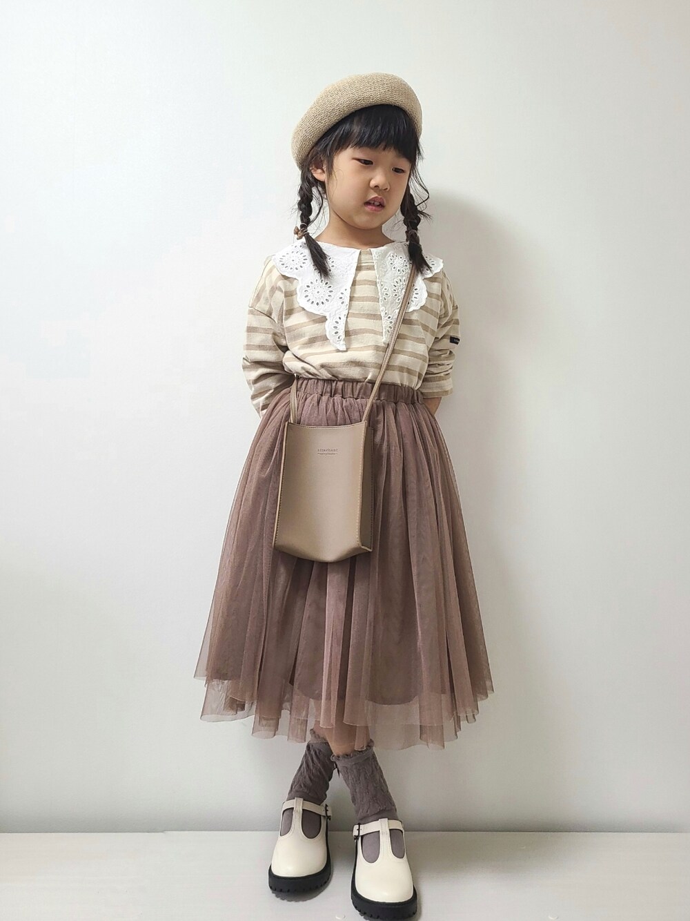 イエロー系のシャツ/ブラウス、ベージュ系のTシャツ/カットソー、ブラウン系のスカートを着用したキッズの冬コーディネートの2枚目の写真