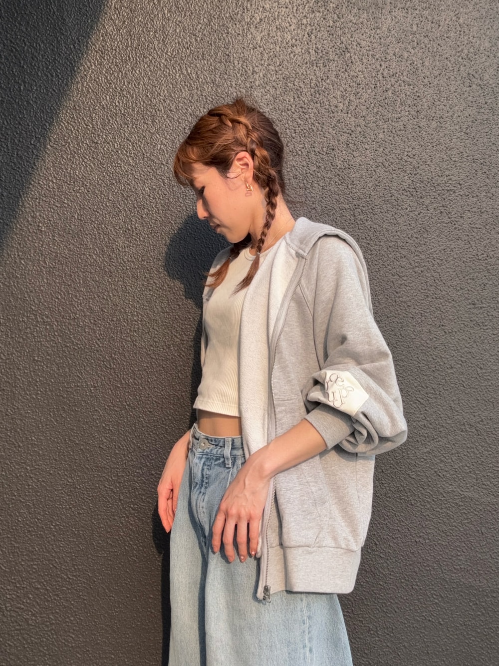 グレー系のスウェット、ブルー系のデニムパンツを着用したレディースの春コーディネートの1枚目の写真