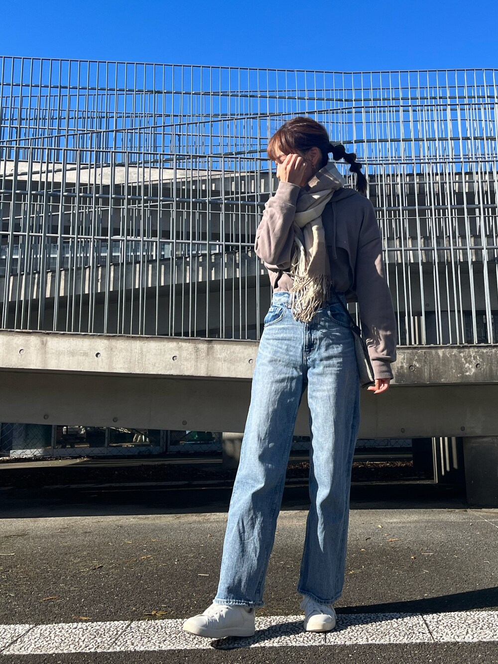 ブラウン系のスウェット、ブルー系のデニムパンツ、ホワイト系のスニーカーを着用したレディースの秋コーディネートの1枚目の写真