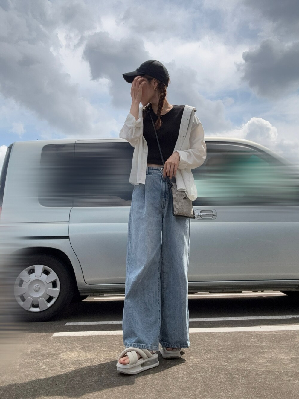 ホワイト系のサンダル、ブルー系のデニムパンツ、ブラック系のショルダーバッグを着用したレディースの春コーディネートの1枚目の写真