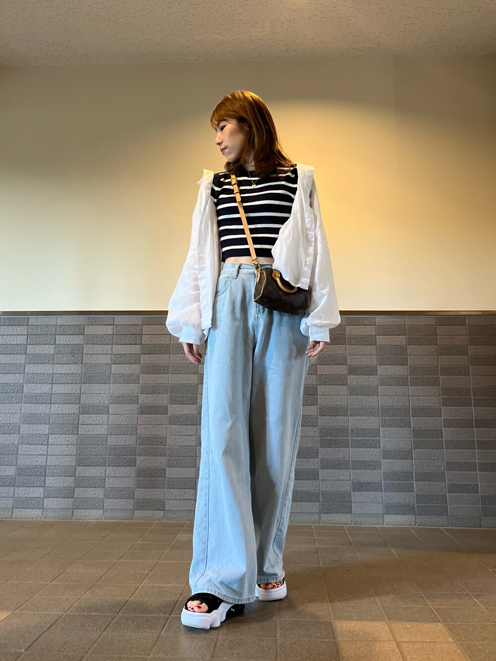 ブルー系のニット/セーター、ブラウン系のバッグ、ホワイト系のシャツ/ブラウスを着用したレディースの夏コーディネートの1枚目の写真