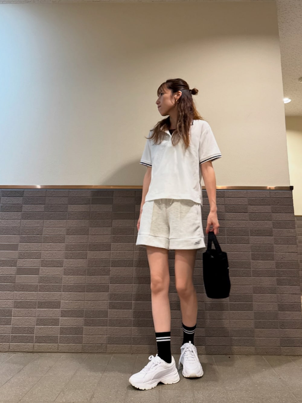 ホワイト系のポロシャツ、グレー系のスウェットパンツ、ブラック系のトートバッグを着用したレディースの夏コーディネートの1枚目の写真