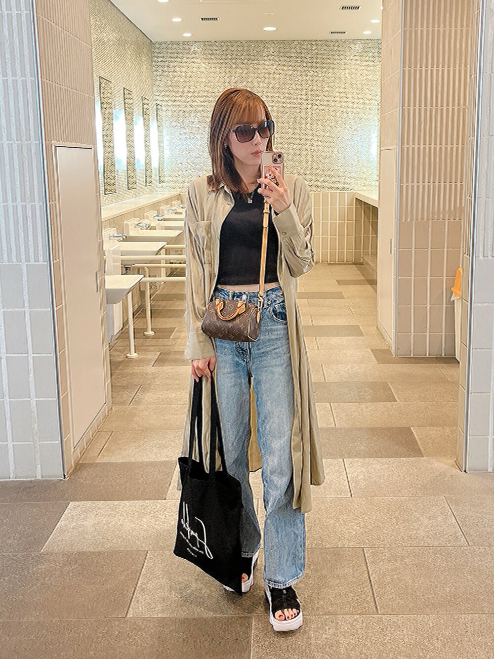 ブルー系のデニムパンツ、ブラック系のトートバッグ、ブラック系のサンダルを着用したレディースの夏コーディネートの1枚目の写真