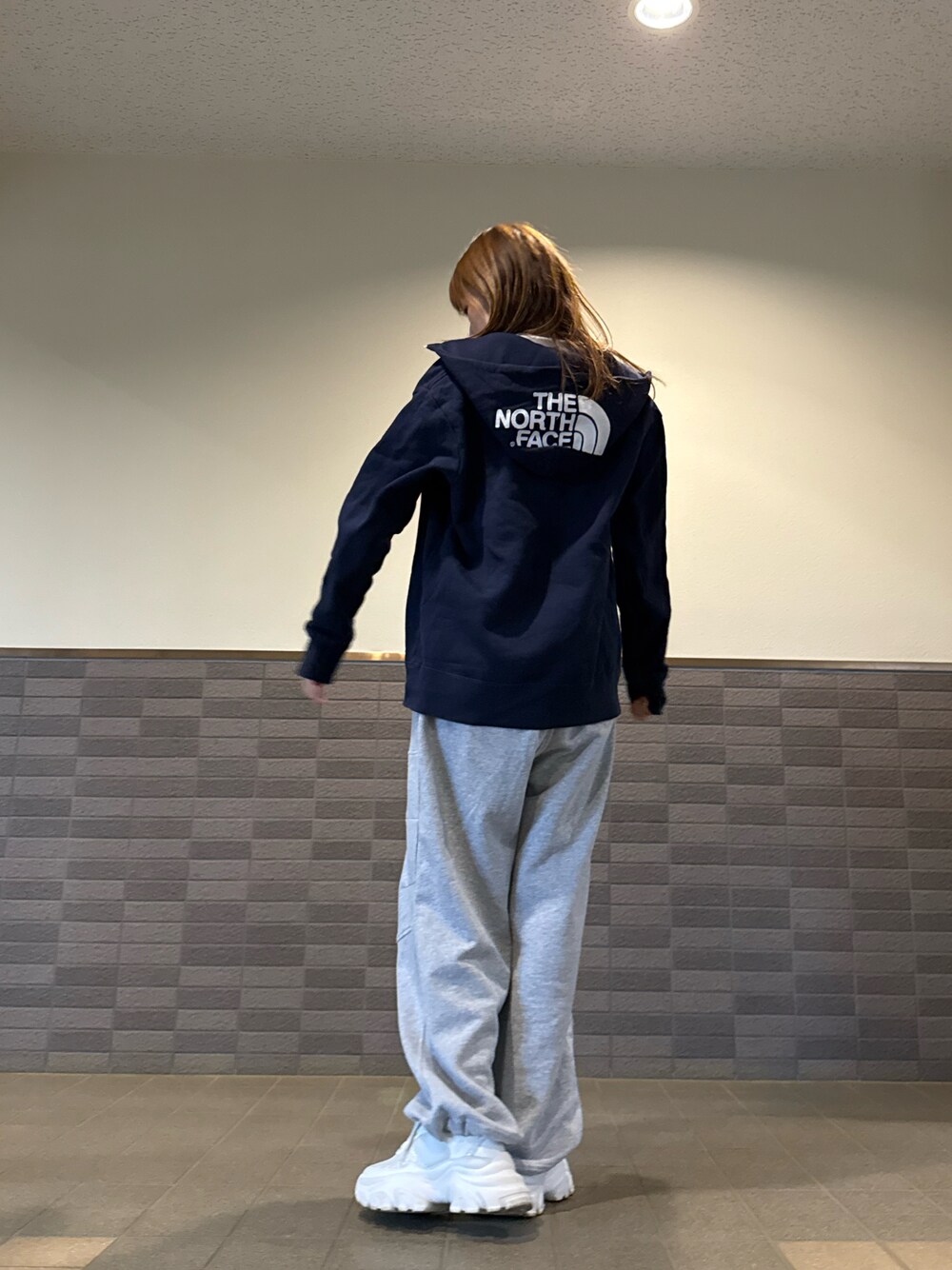 グレー系のスウェットパンツ、ブルー系のパーカー、ホワイト系のスニーカーを着用したレディースの春コーディネートの1枚目の写真