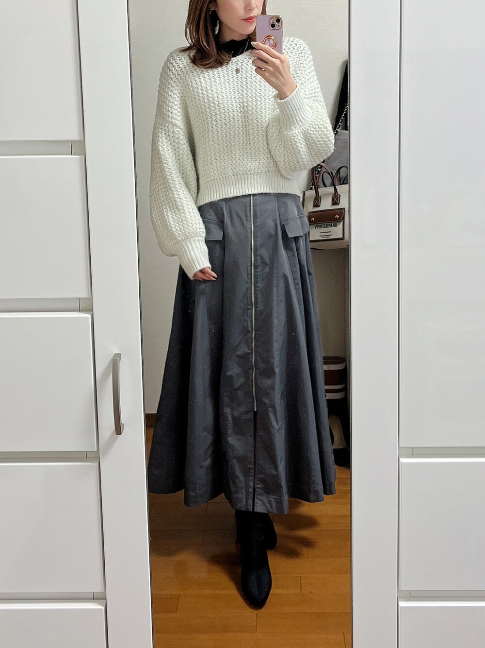 ホワイト系のニット/セーター、ブラック系のTシャツ/カットソー、グレー系のスカートを着用したレディースの冬コーディネートの1枚目の写真
