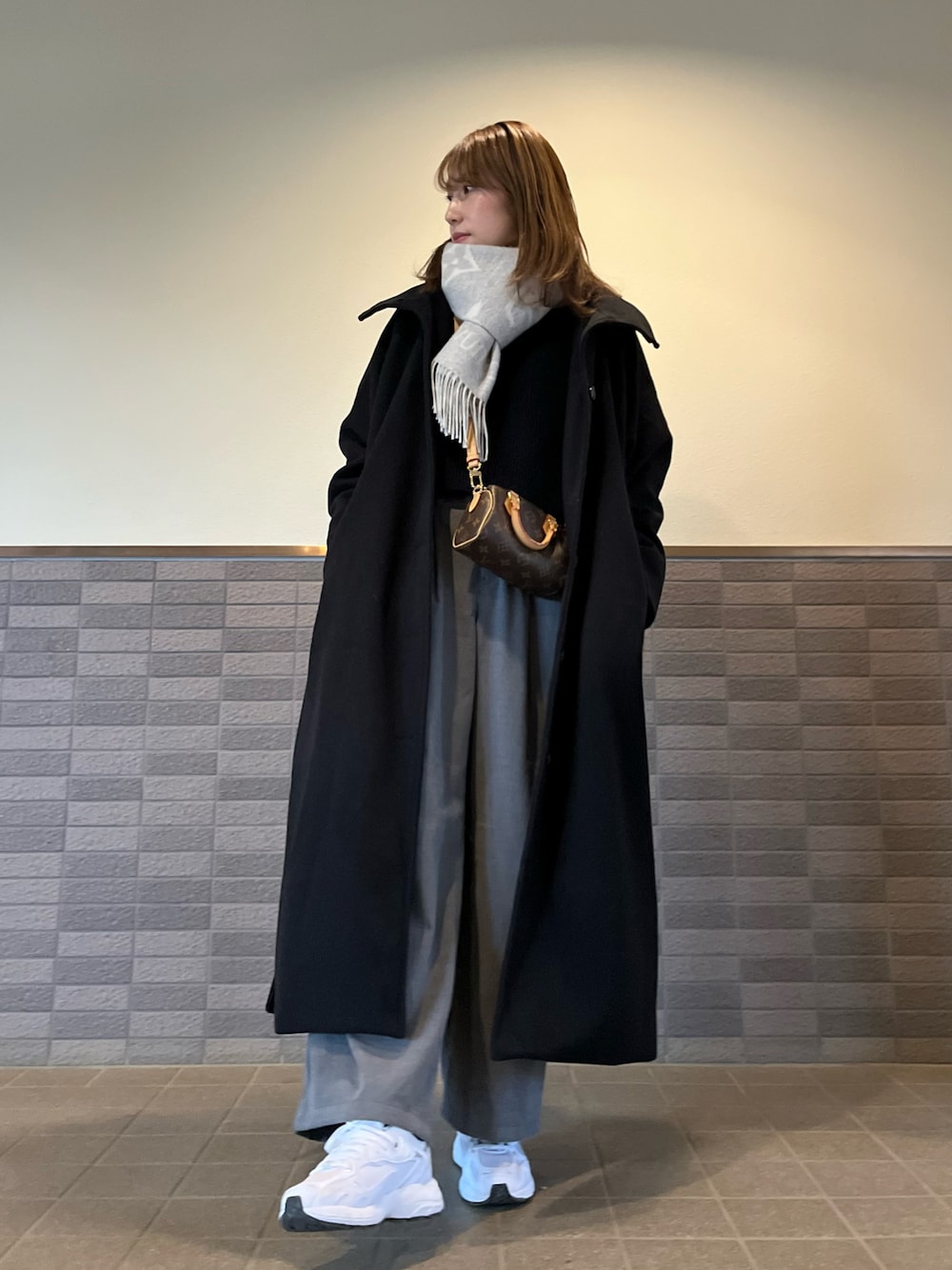 ブラック系のその他アウター、グレー系のパンツ、ブラウン系のバッグを着用したレディースの冬コーディネートの1枚目の写真