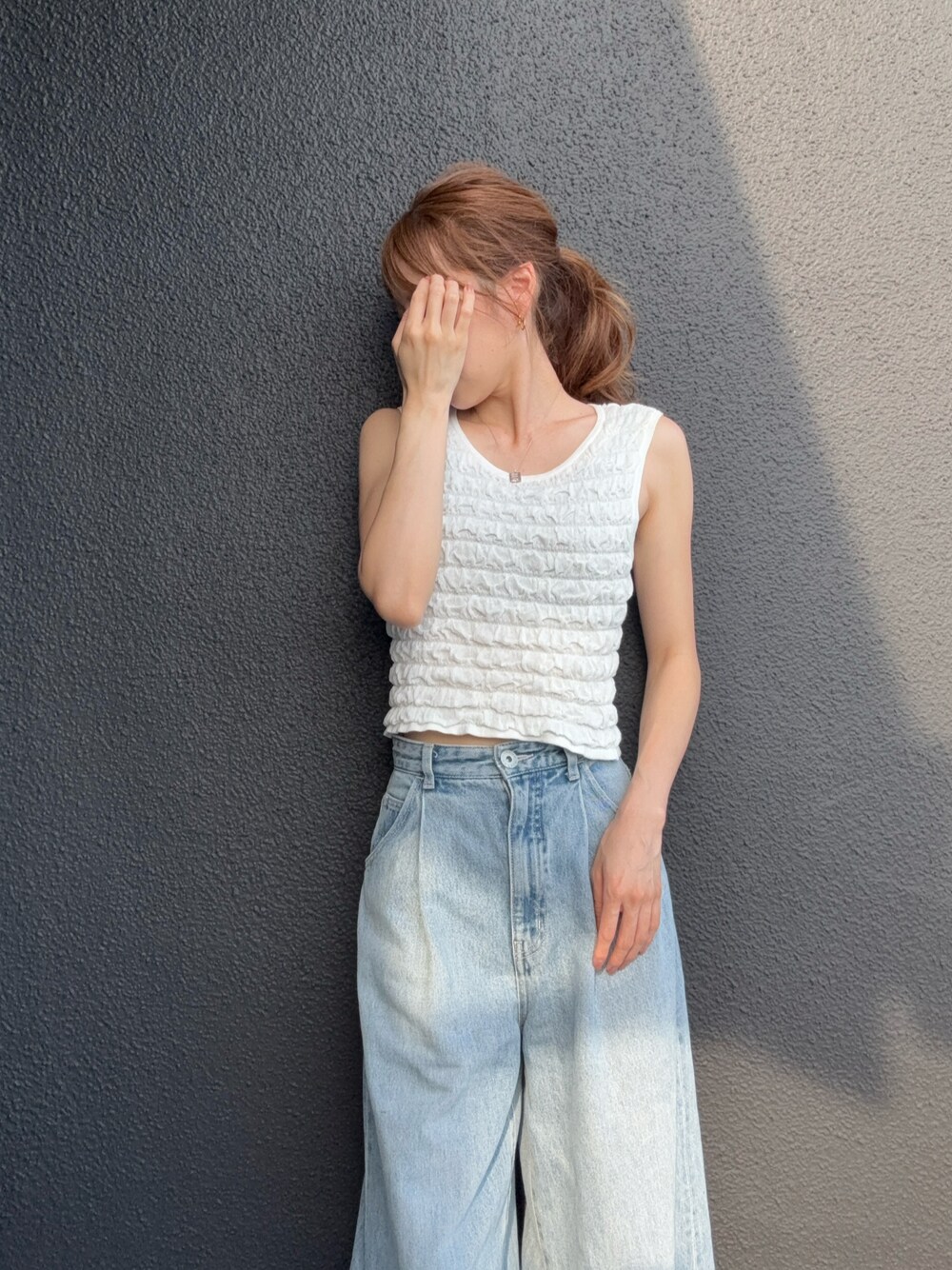 ホワイト系のニット/セーター、ブルー系のデニムパンツを着用したレディースの夏コーディネートの1枚目の写真