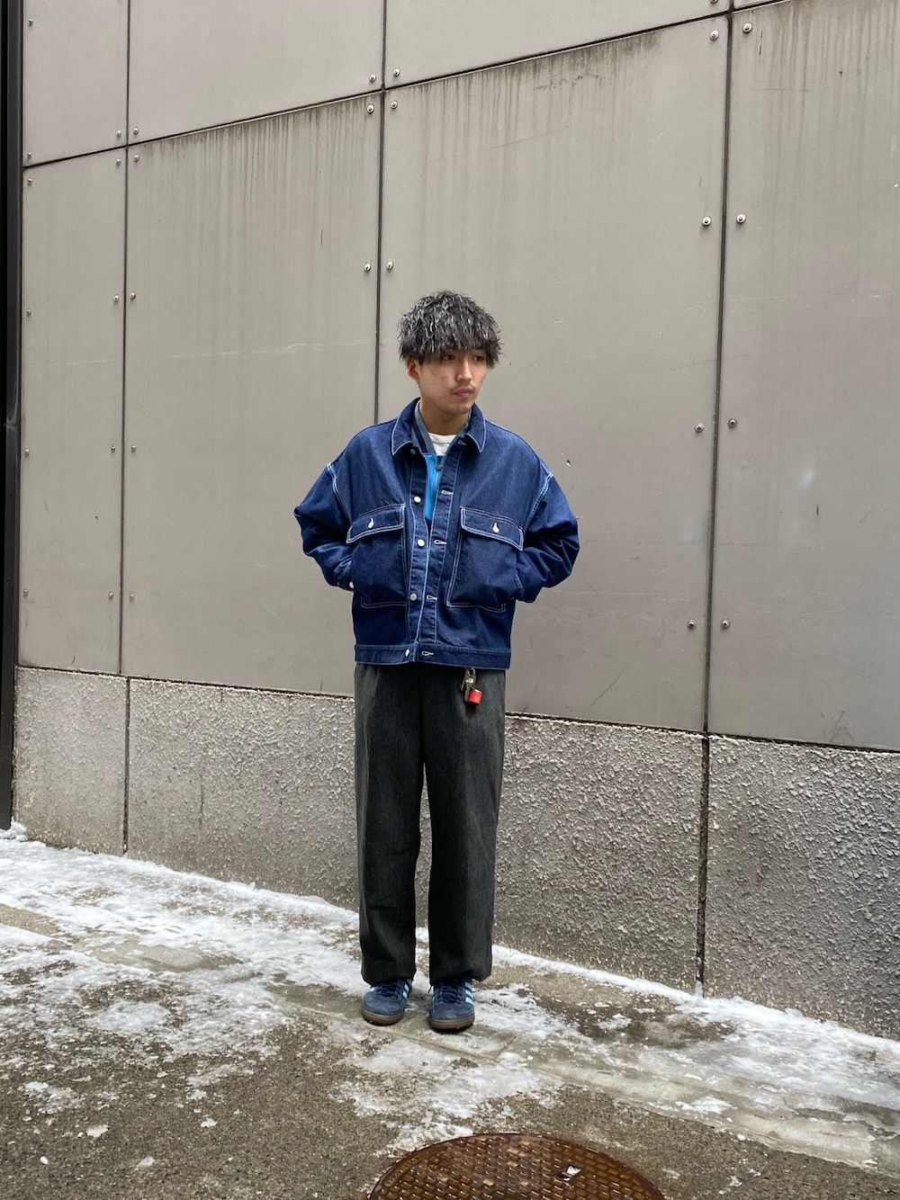 ブルー系のデニムジャケット、グレー系のスラックス、ブルー系のスニーカーを着用したメンズの冬コーディネートの1枚目の写真