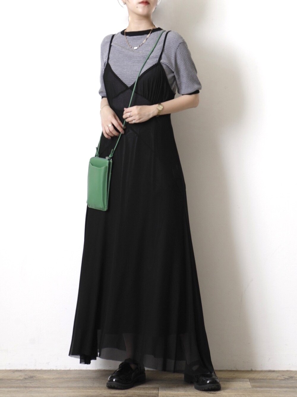 グリーン系のショルダーバッグ、ブラック系のワンピース、ブラウン系のローファーを着用したレディースの夏コーディネートの1枚目の写真