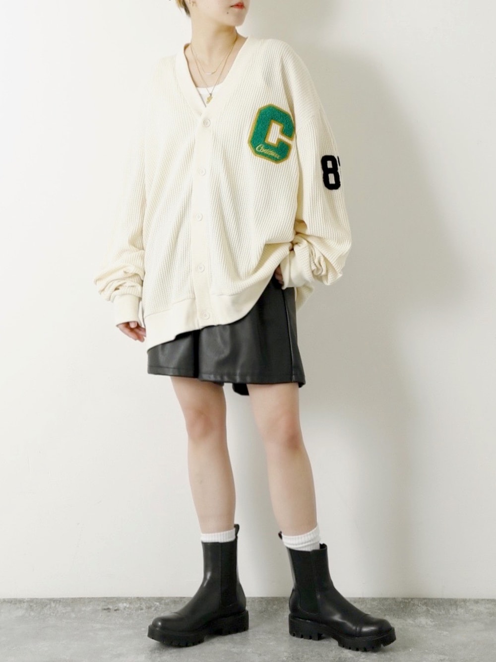 ホワイト系のカーディガン/ボレロ、ブラック系のブーツを着用したレディースの春コーディネートの1枚目の写真