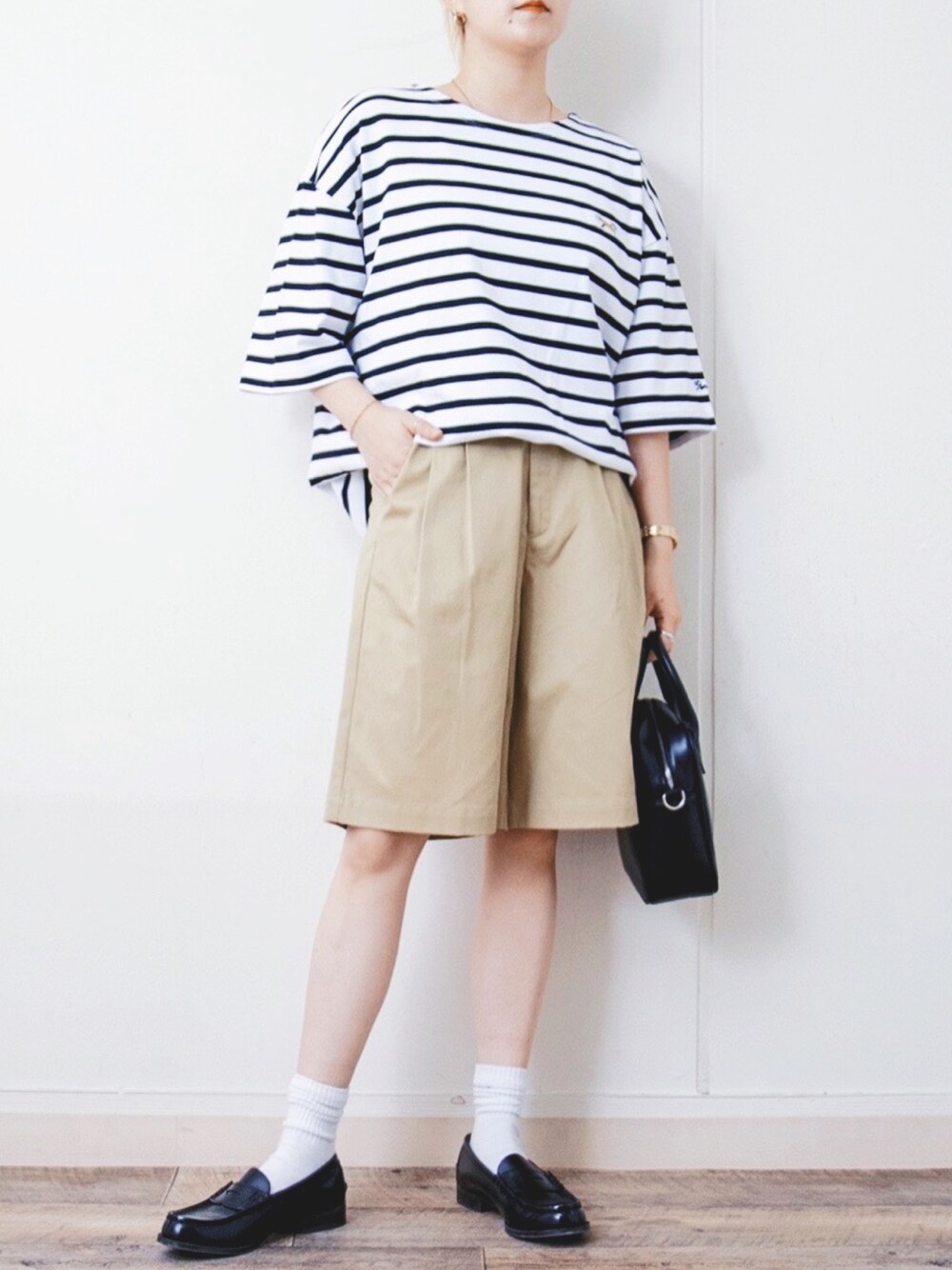 ホワイト系のTシャツ/カットソー、ベージュ系のチノパンツ、ブラック系のボストンバッグを着用したレディースの春コーディネートの1枚目の写真