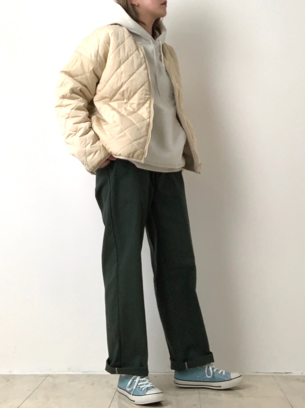 グリーン系のチノパンツ、ブルー系のスニーカー、ホワイト系のブルゾンを着用したレディースの冬コーディネートの1枚目の写真