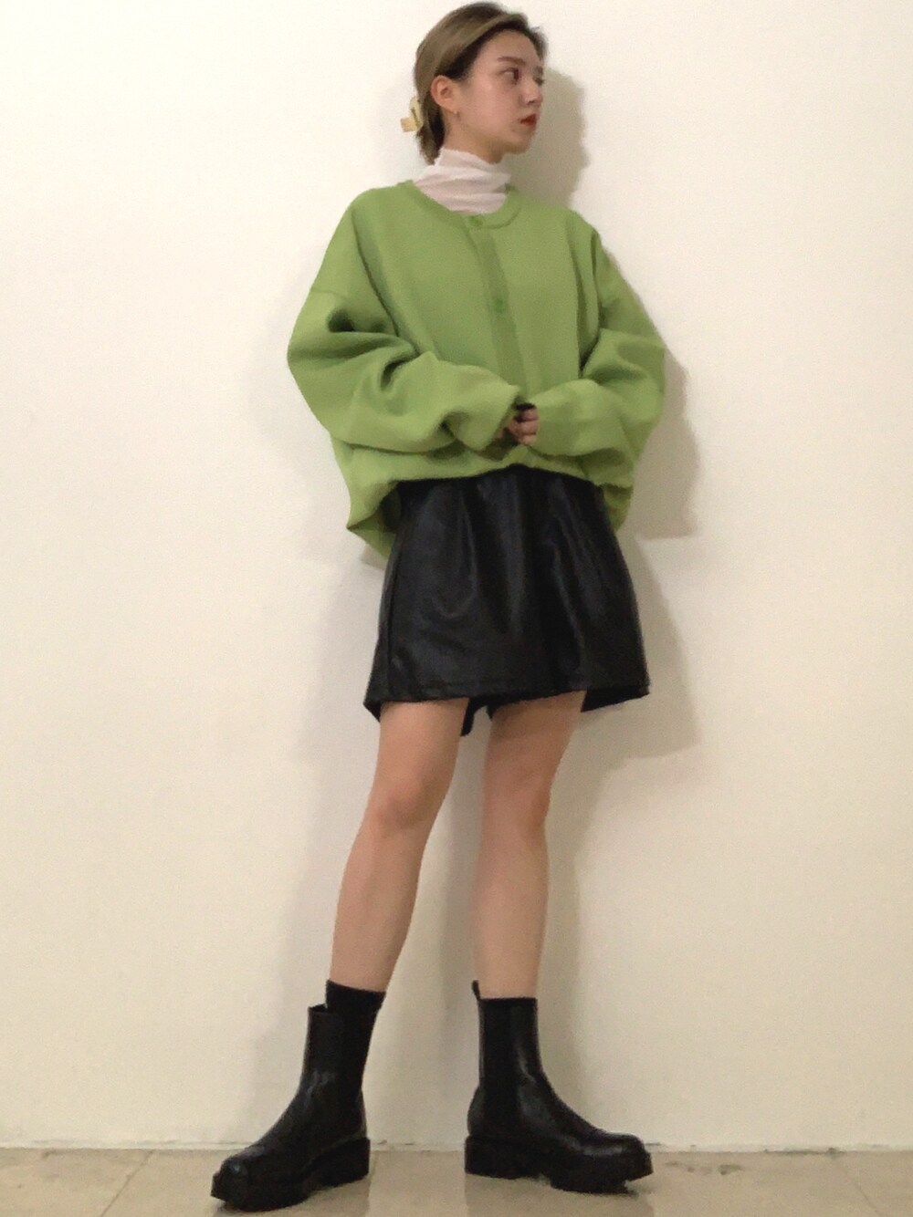 グリーン系のカーディガン/ボレロ、ホワイト系のTシャツ/カットソー、ブラック系のブーツを着用したレディースの冬コーディネートの1枚目の写真