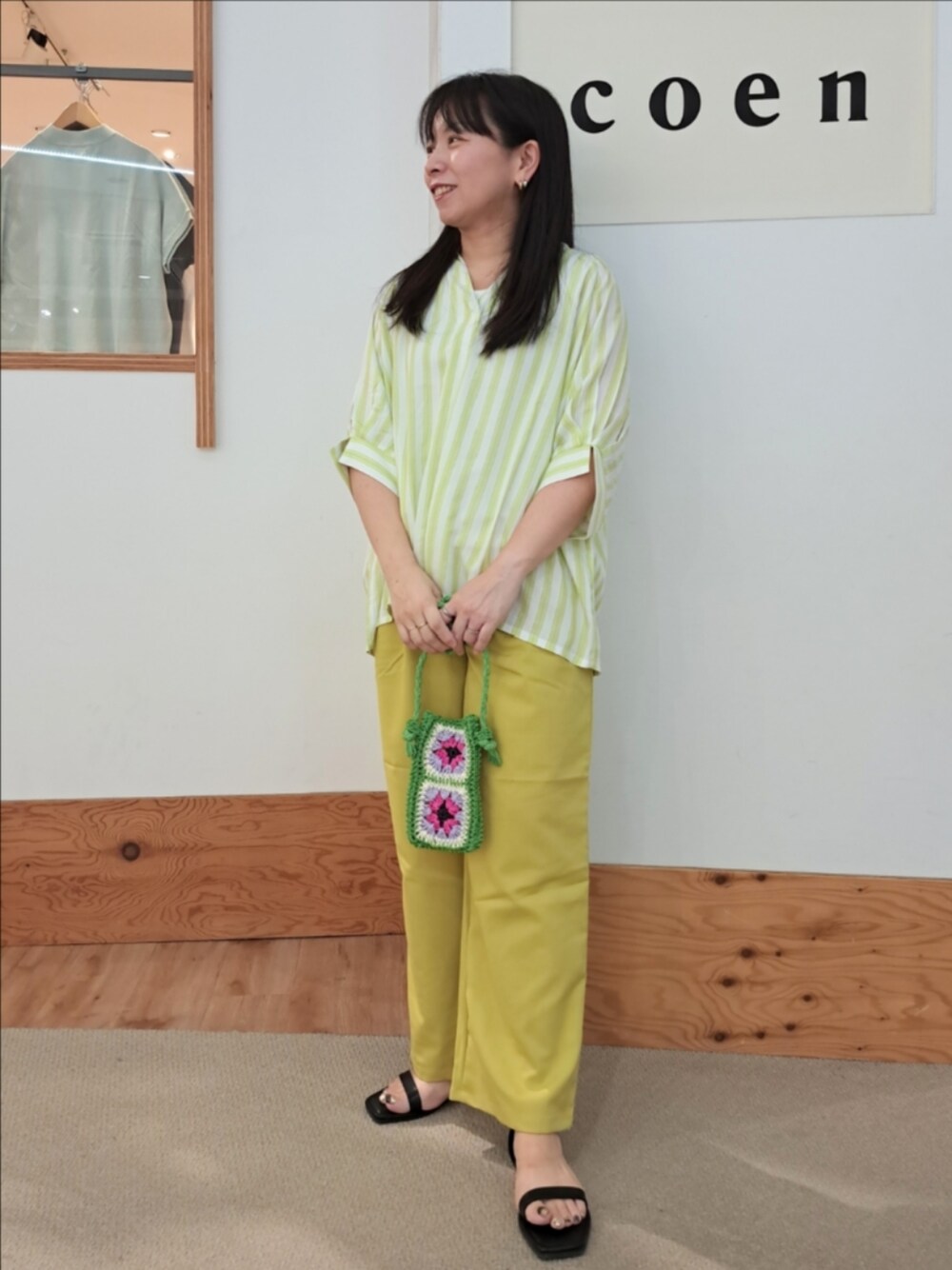 グリーン系のシャツ/ブラウス、イエロー系のスラックス、ホワイト系のタンクトップを着用したレディースの春コーディネートの1枚目の写真