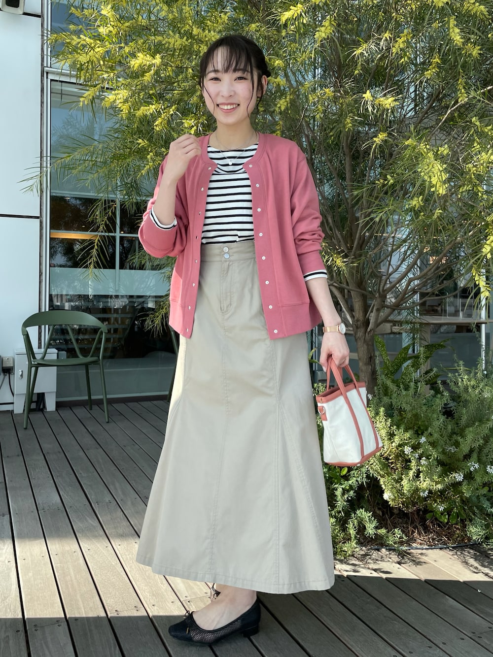 ピンク系のカーディガン/ボレロ、ブラック系のTシャツ/カットソー、ベージュ系のスカートを着用したレディースの春コーディネートの1枚目の写真