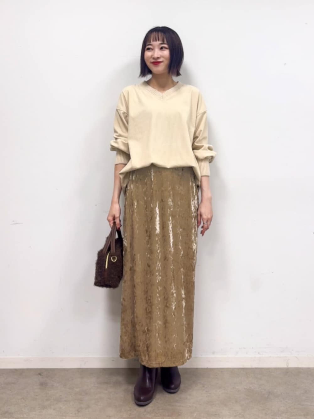 ベージュ系のスカート、ホワイト系のTシャツ/カットソー、ブラウン系のブーツを着用したレディースの秋コーディネートの1枚目の写真