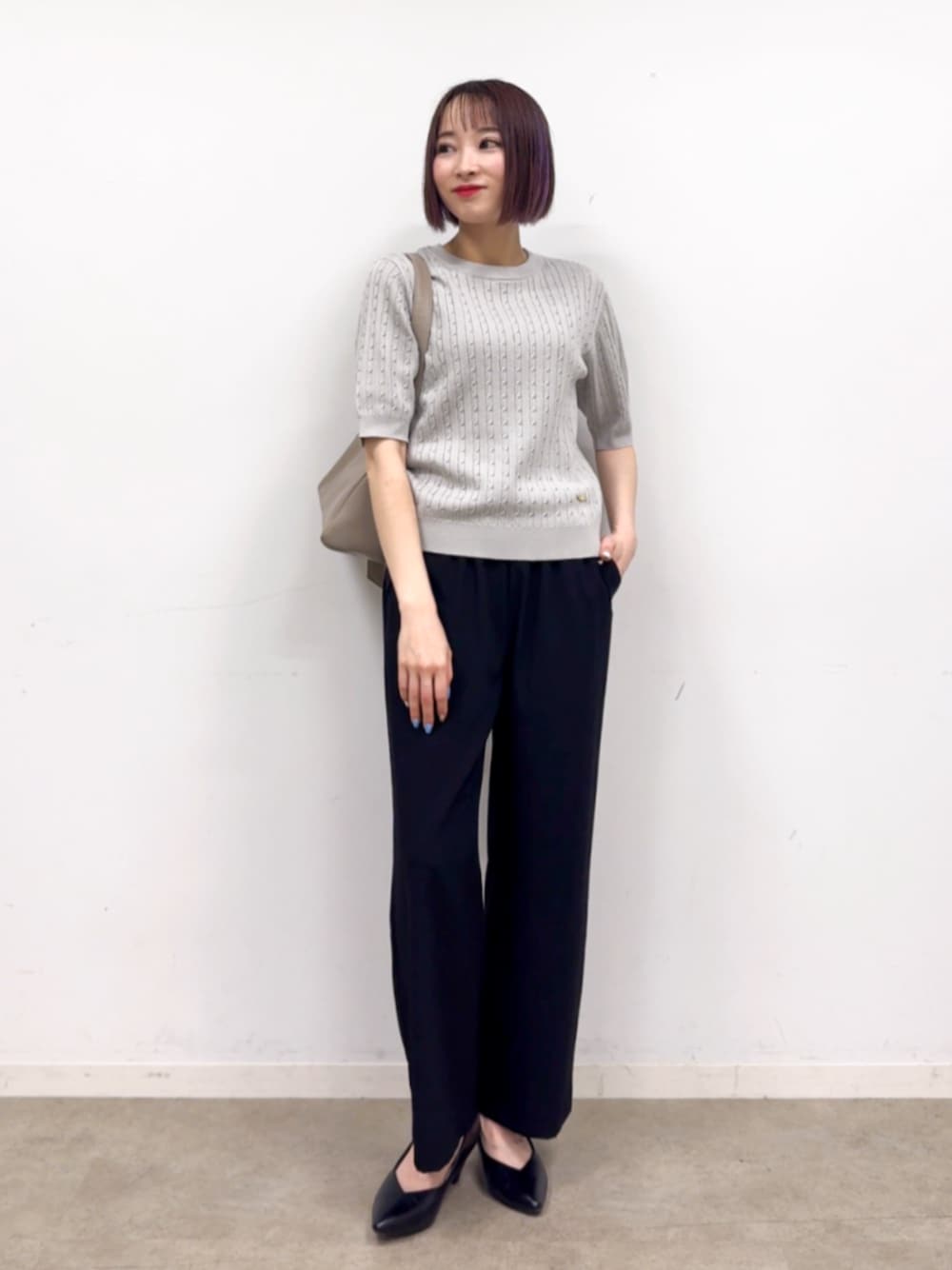 ブラック系のパンプス、ベージュ系のショルダーバッグ、グレー系のニット/セーターを着用したレディースの春コーディネートの1枚目の写真