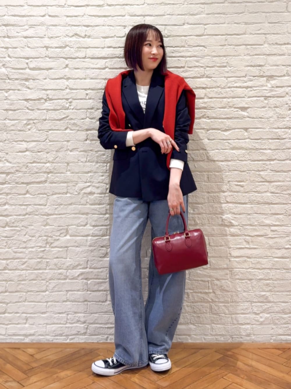 レッド系のカーディガン/ボレロ、ブルー系のテーラードジャケット、ブルー系のデニムパンツを着用したレディースの冬コーディネートの1枚目の写真