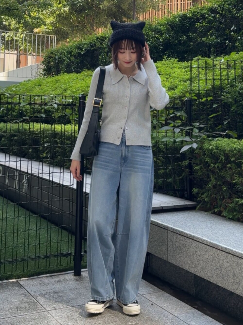 ブラック系のショルダーバッグ、ブルー系のデニムパンツ、グレー系のニット/セーターを着用したレディースの秋コーディネートの1枚目の写真