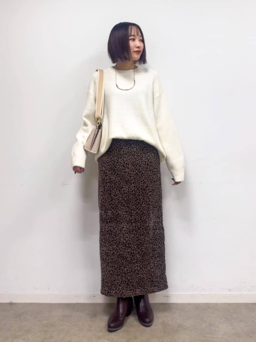 ブラウン系のブーツ、ホワイト系のニット/セーター、ブラウン系のスカートを着用したレディースの冬コーディネートの1枚目の写真