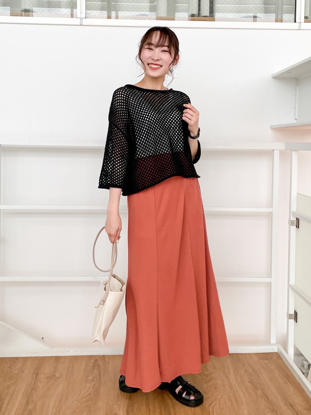 ブラック系のその他トップス、オレンジ系のスカート、ブラック系のサンダルを着用したレディースの春コーディネートの1枚目の写真