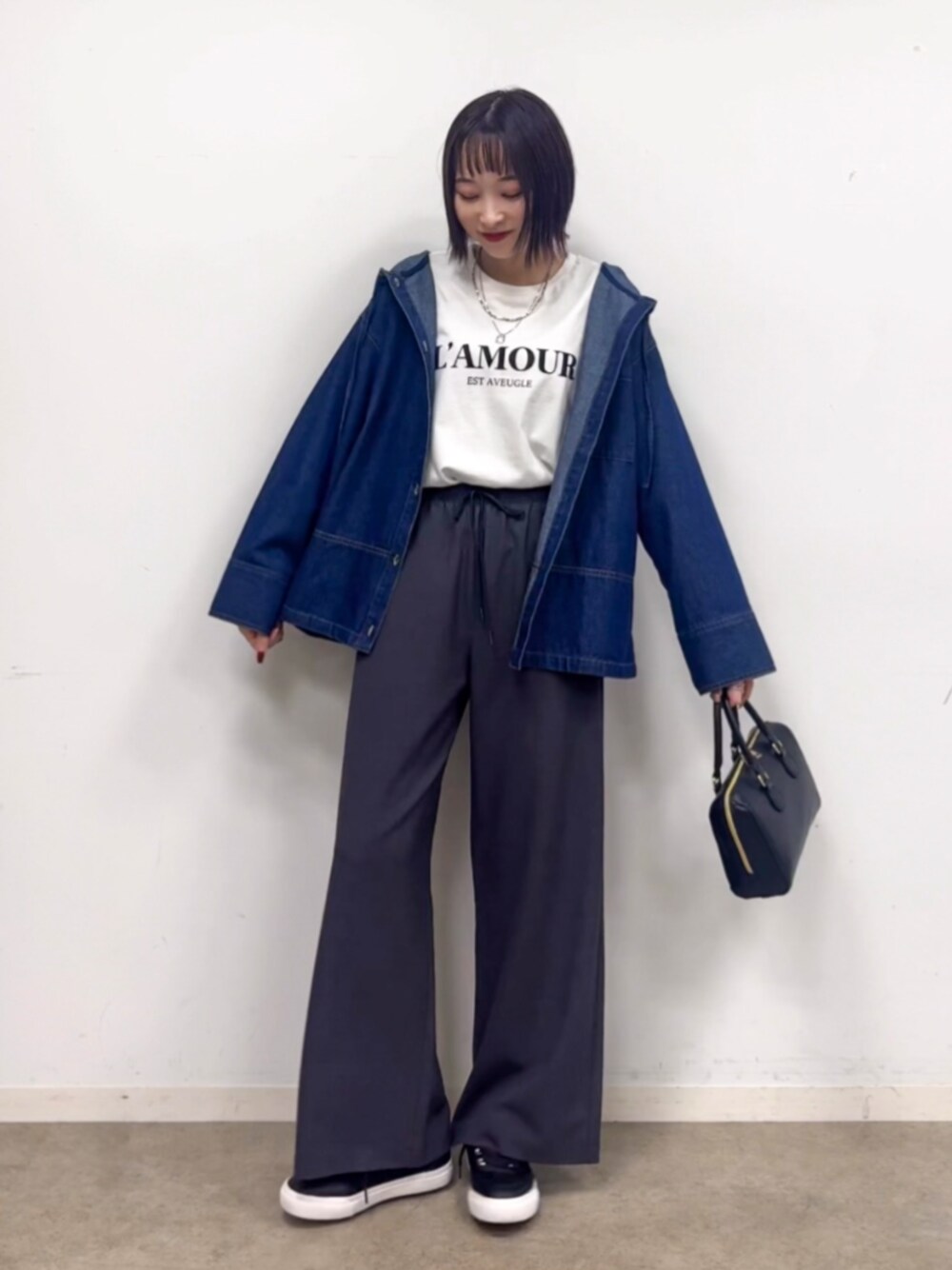 ブラック系のショルダーバッグ、ブラック系のスニーカー、ホワイト系のTシャツ/カットソーを着用したレディースの秋コーディネートの1枚目の写真