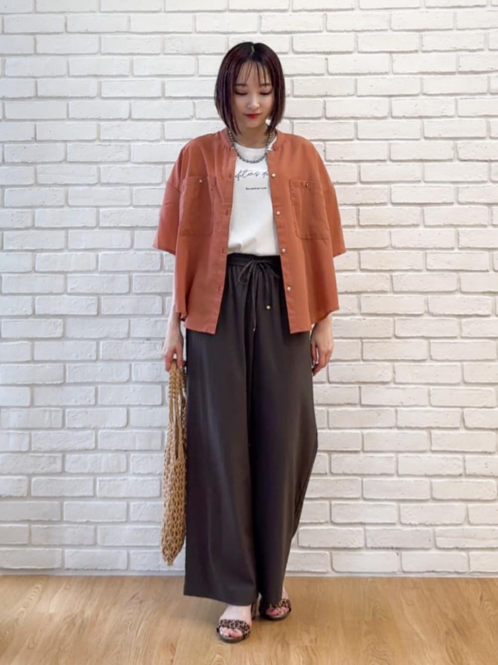 ブラウン系のサンダル、オレンジ系のシャツ/ブラウス、ホワイト系のTシャツ/カットソーを着用したレディースの夏コーディネートの1枚目の写真