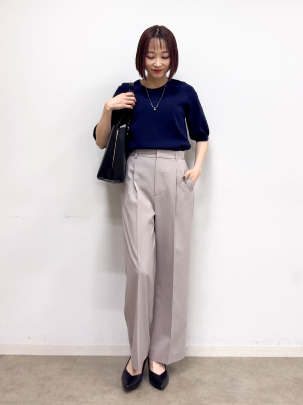 ブラック系のパンプス、ブラック系のトートバッグ、ブルー系のニット/セーターを着用したレディースの春コーディネートの1枚目の写真
