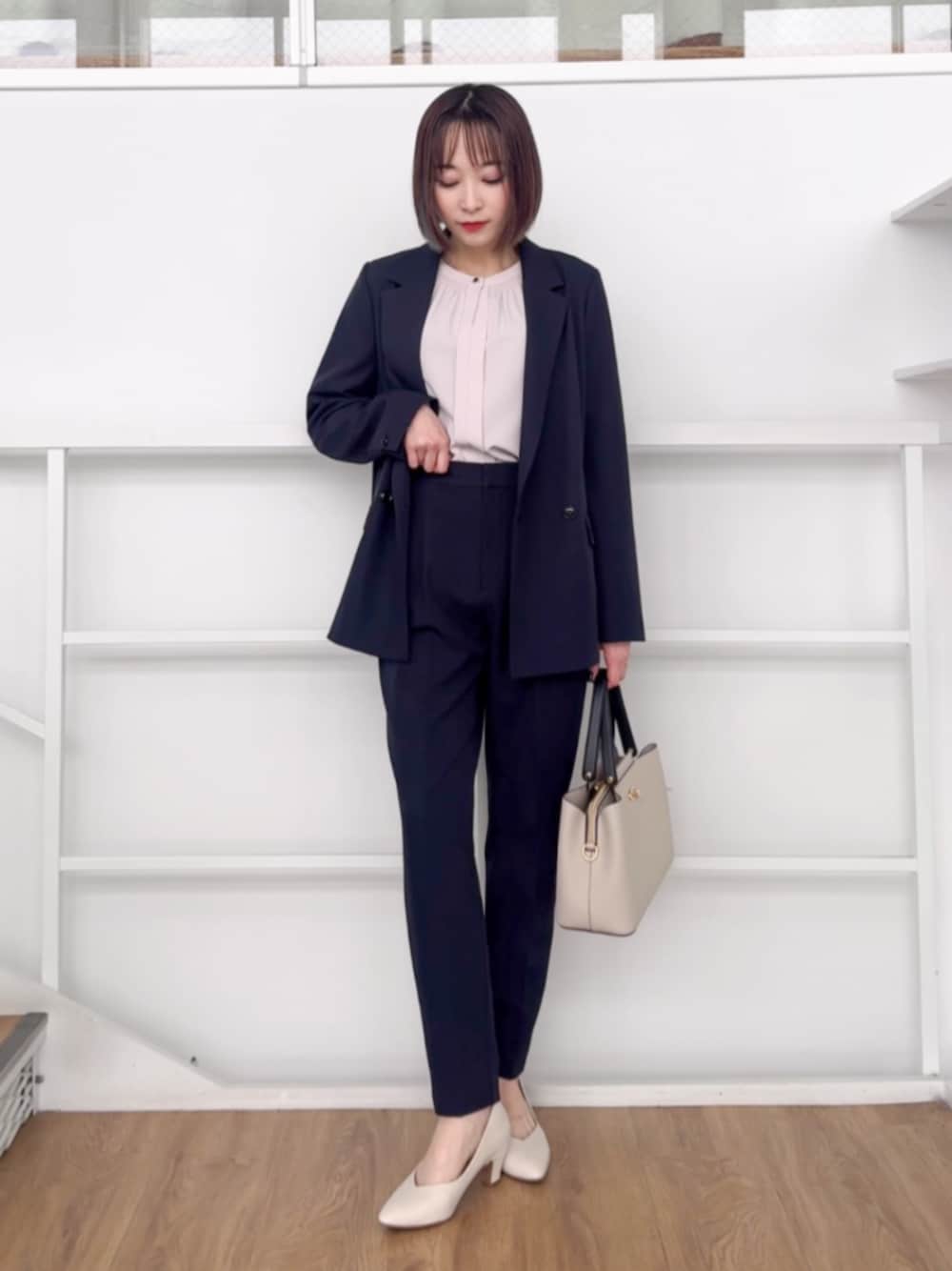 グレー系のトートバッグ、ホワイト系のパンプス、ブルー系のテーラードジャケットを着用したレディースの春コーディネートの1枚目の写真