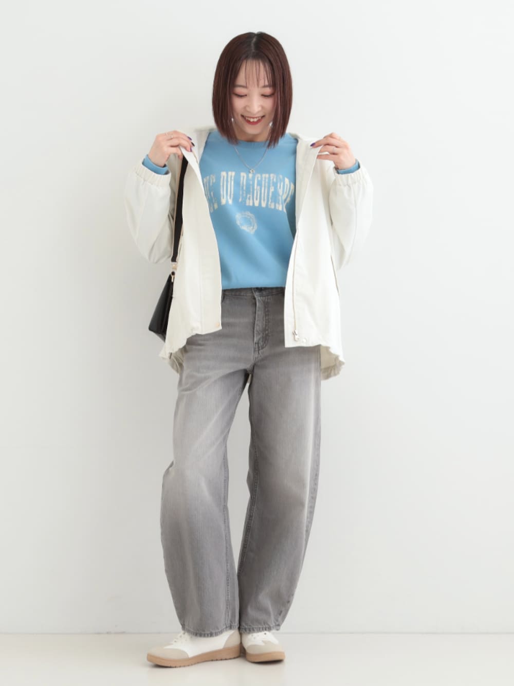 グレー系のデニムパンツ、ブラック系のショルダーバッグ、ホワイト系のスニーカーを着用したレディースの春コーディネートの1枚目の写真