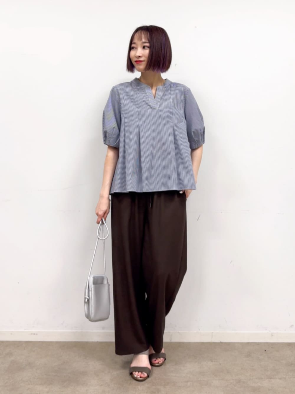 ブラウン系のその他パンツ、シルバー系のショルダーバッグ、ブルー系のシャツ/ブラウスを着用したレディースの春コーディネートの1枚目の写真