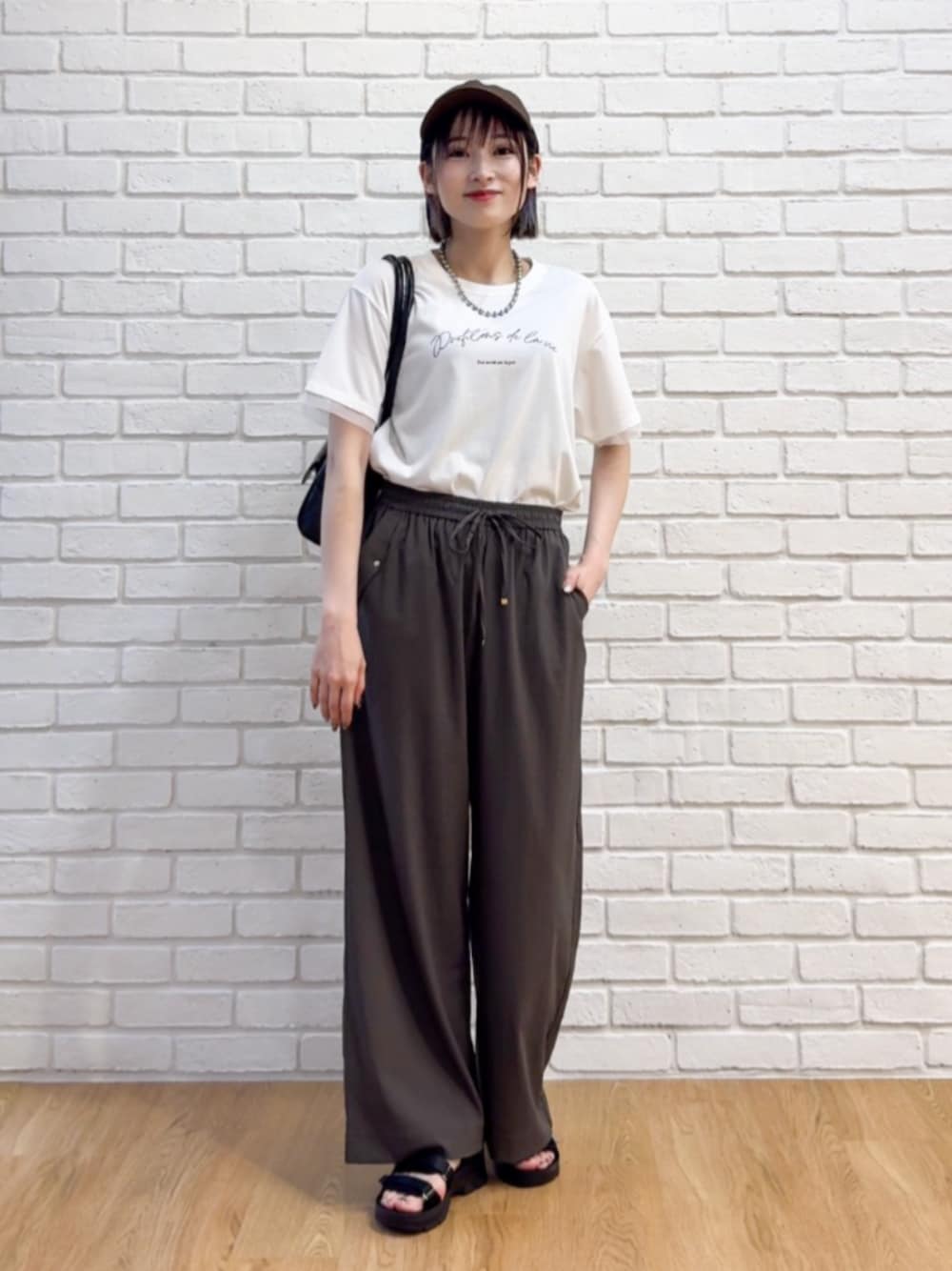 ブラック系のボストンバッグ、ブラック系のサンダル、ホワイト系のTシャツ/カットソーを着用したレディースの夏コーディネートの1枚目の写真