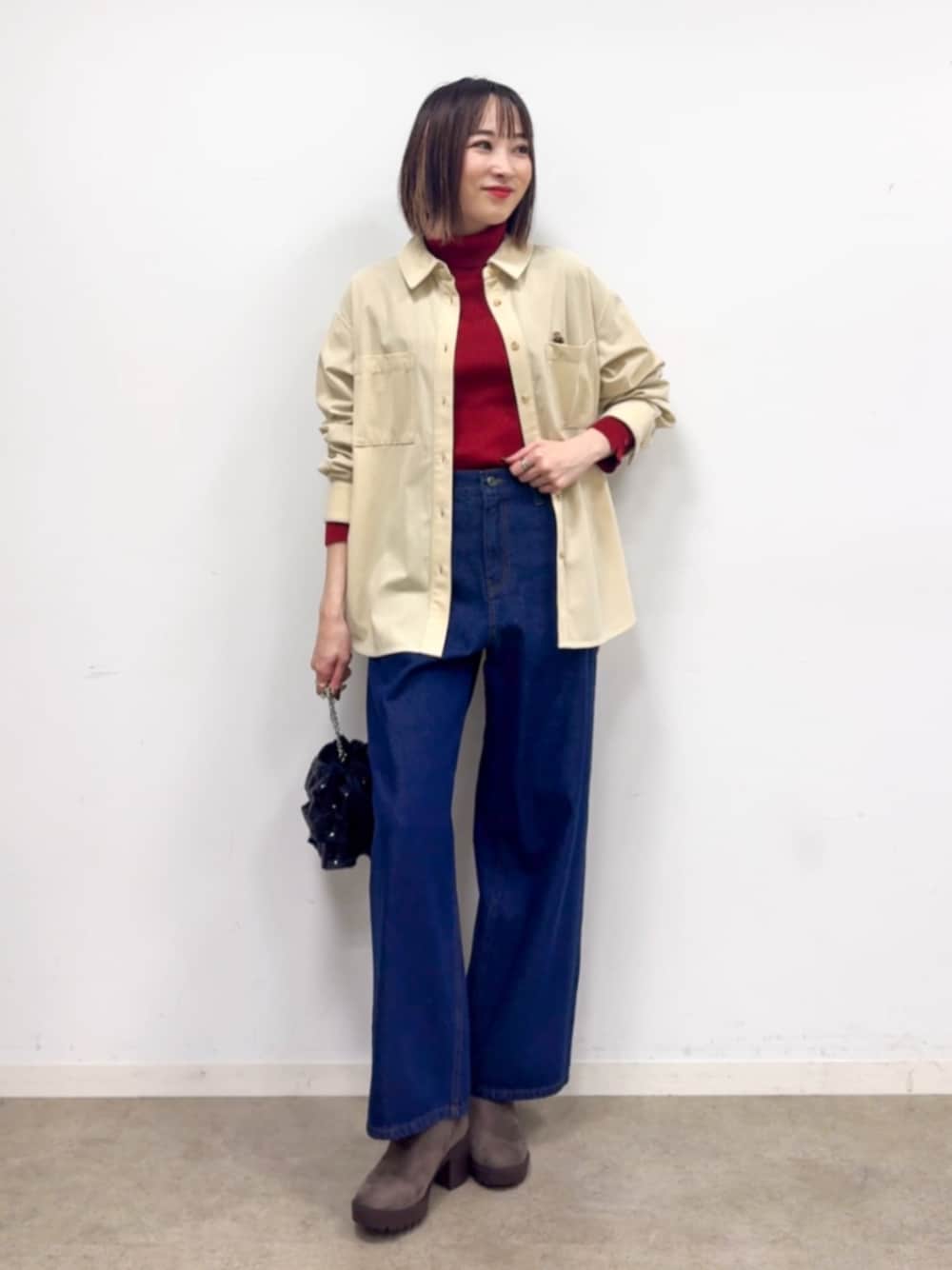 レッド系のニット/セーター、ブルー系のデニムパンツ、ブラウン系のブーツを着用したレディースの冬コーディネートの1枚目の写真