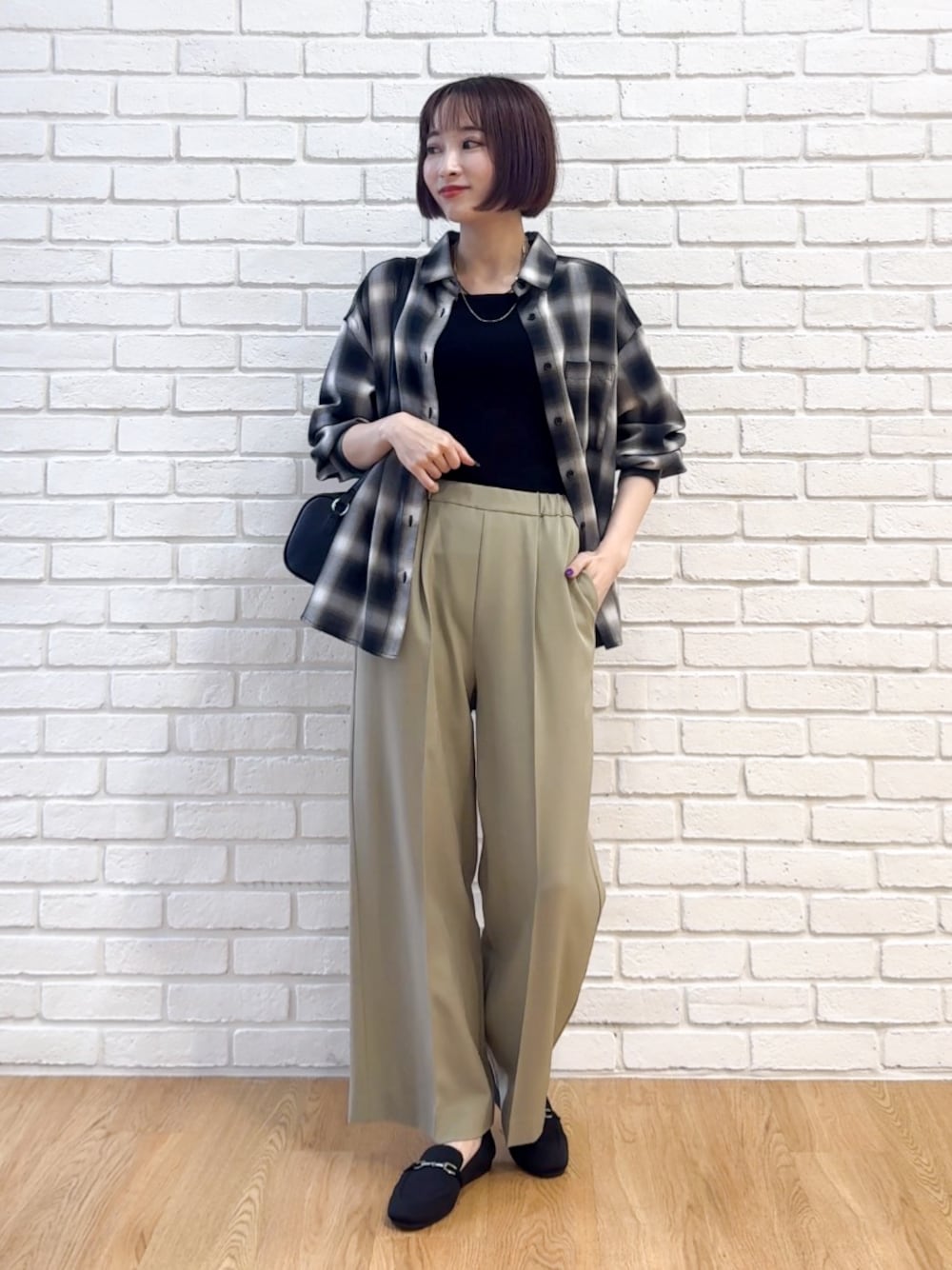 グレー系のシャツ/ブラウス、ブラック系のニット/セーター、グリーン系のその他パンツを着用したレディースの秋コーディネートの1枚目の写真