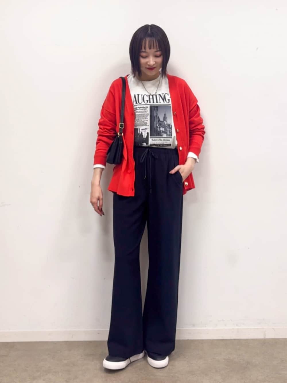 ブラック系のショルダーバッグ、ブラック系のスニーカー、オレンジ系のカーディガン/ボレロを着用したレディースの秋コーディネートの1枚目の写真