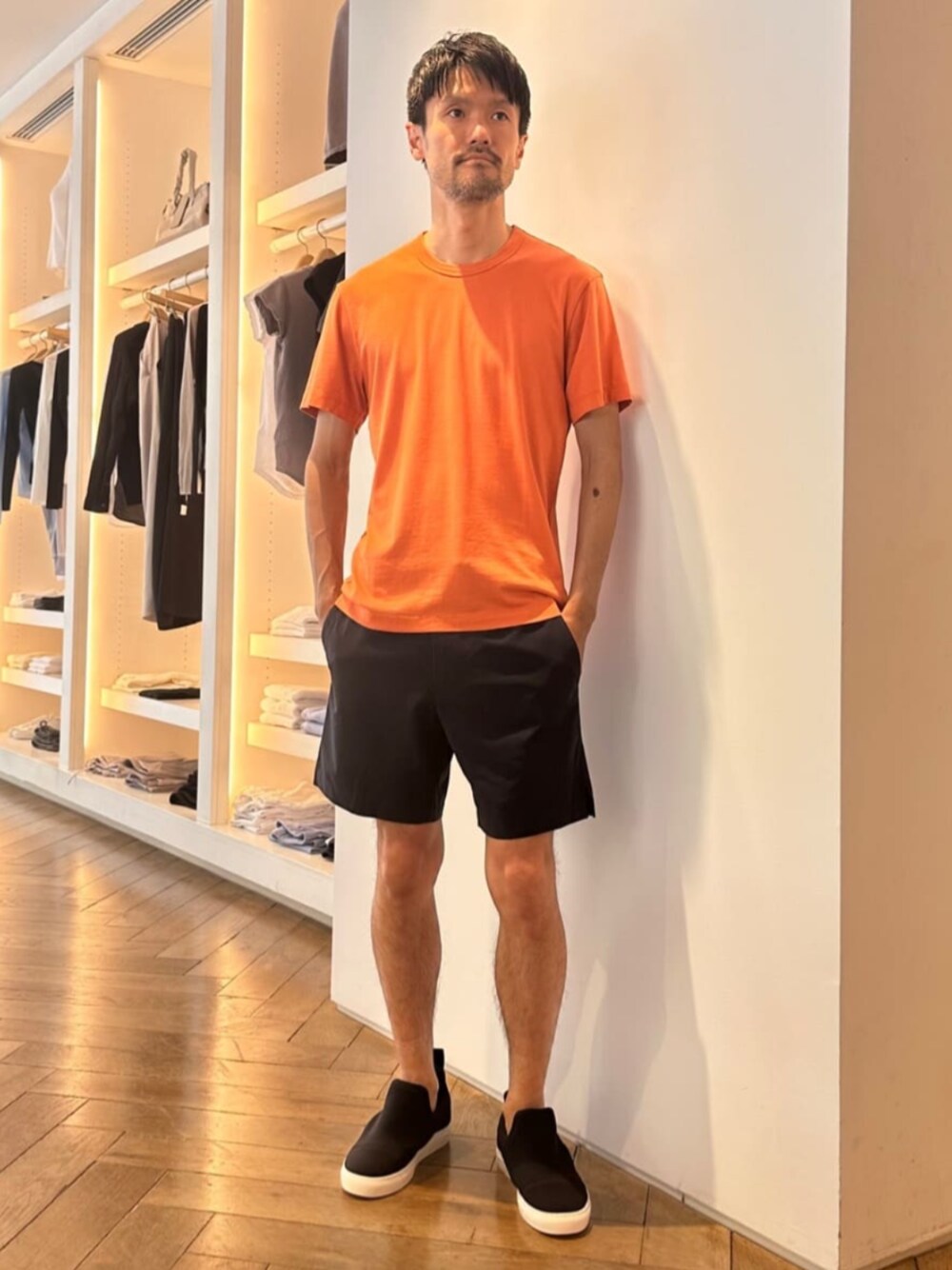 「TOMORROWLAND、トゥモローランド、JAMES PERSE、YOSEMITE、オレンジ、ショートパンツ、Tシャツ、スリッポン、デイリーカジュアル、リラックススタイル」｜「JAMES PERSEのZUMA スキューバ スリッポンシューズ SMZU8174（スニーカー、ブラック系）」を使った、Wada_TOMORROWLANDさん（メンズ・174cm）の春コーディネートの1枚目の写真