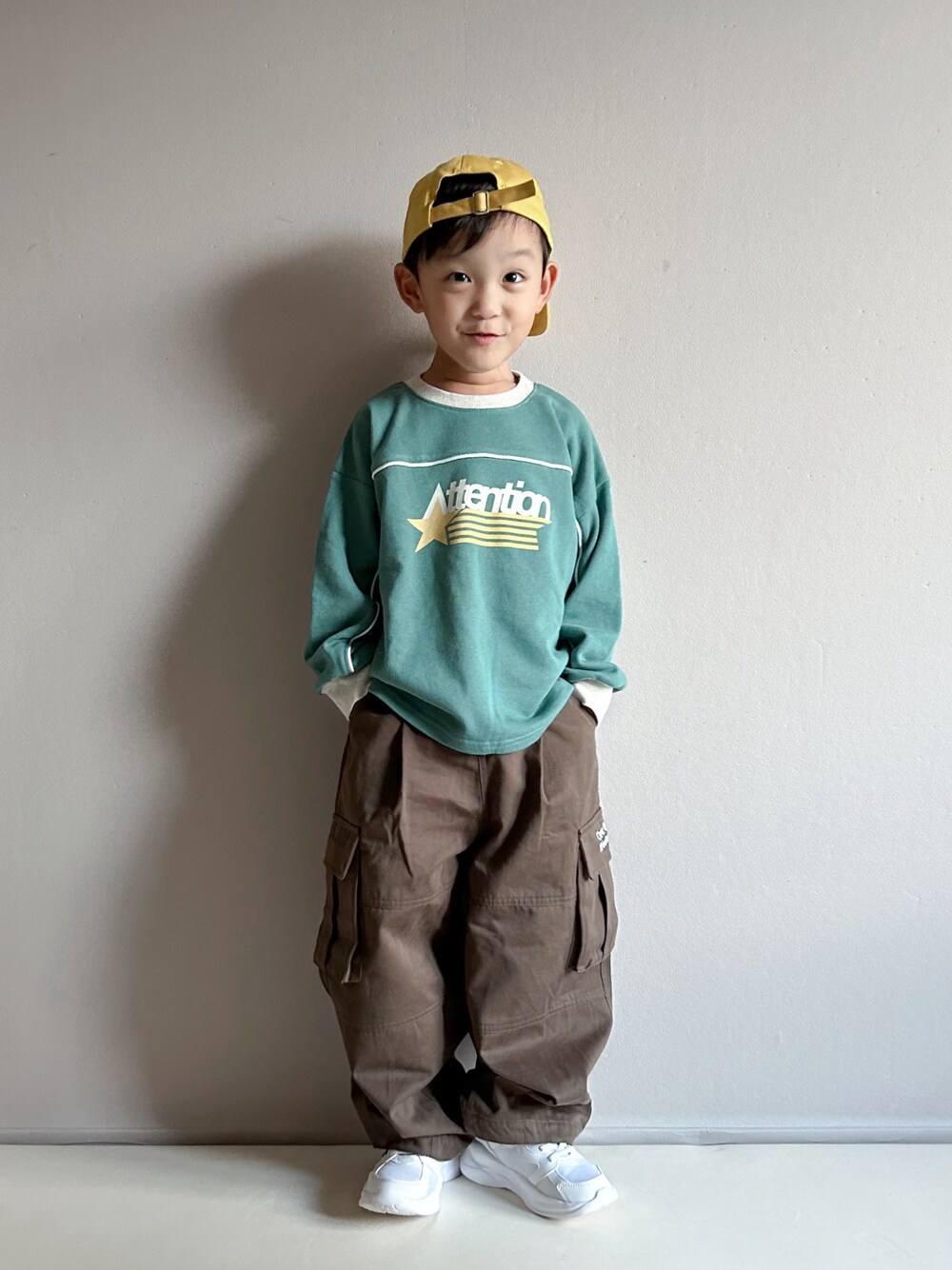 グリーン系のスウェット、ベージュ系のカーゴパンツ、ホワイト系のスニーカーを着用したキッズの秋コーディネートの1枚目の写真