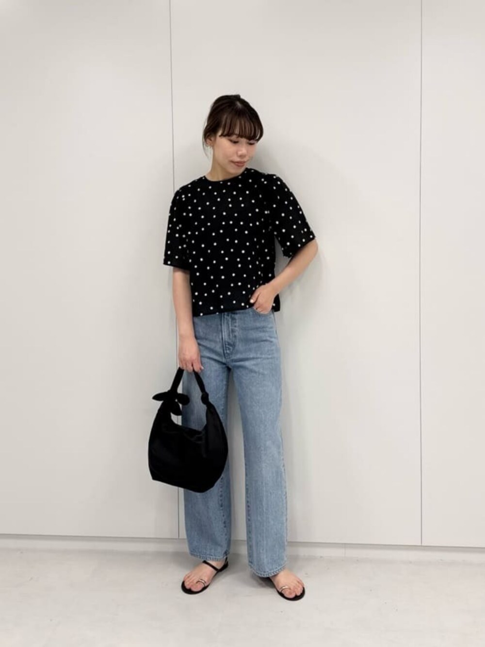 ブルー系のデニムパンツ、ブラック系のショルダーバッグ、ブラック系のシャツ/ブラウスを着用したレディースの夏コーディネートの1枚目の写真
