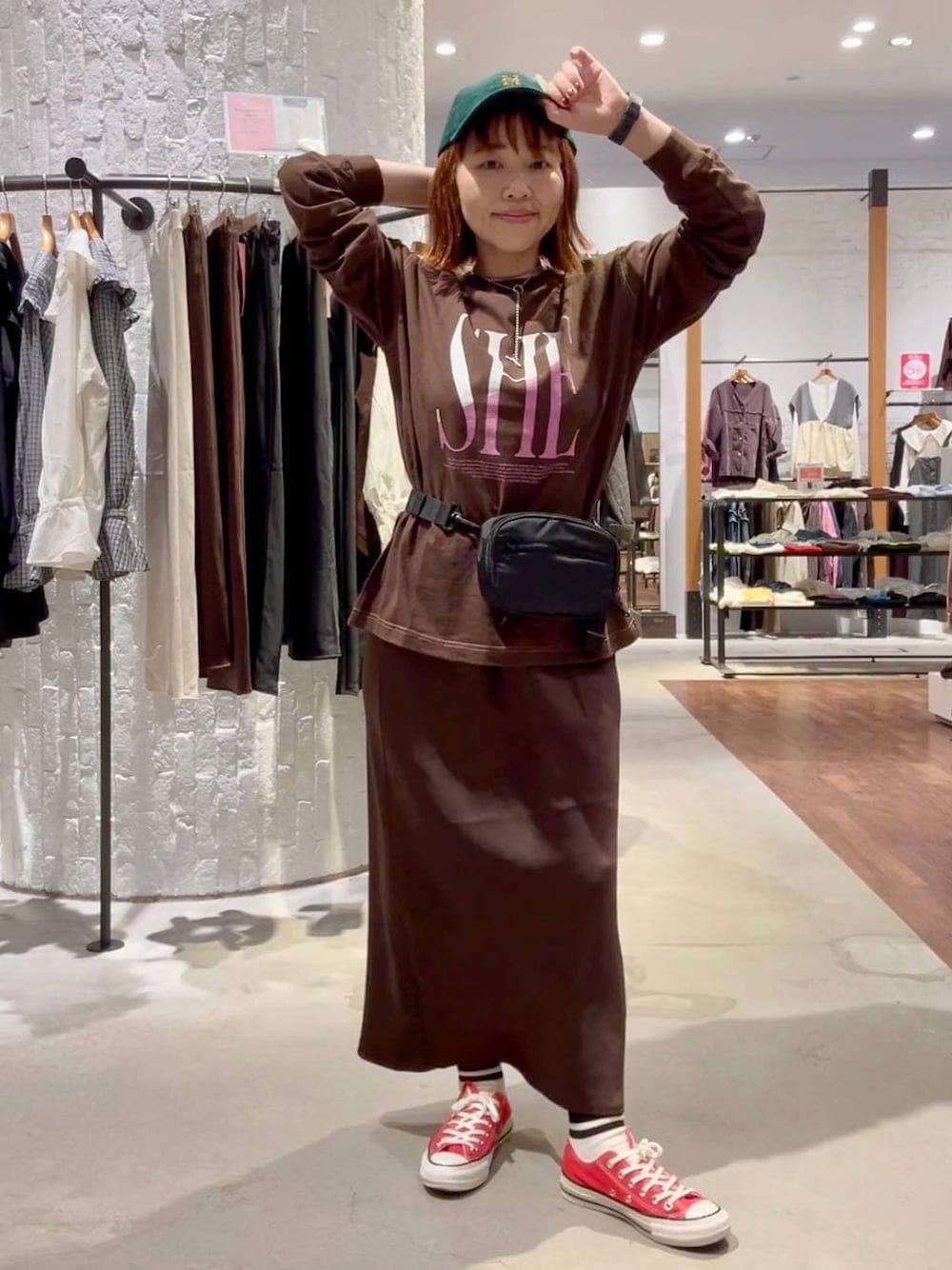 ブラウン系のスカート、ブラウン系のTシャツ/カットソー、レッド系のスニーカーを着用したレディースの秋コーディネートの1枚目の写真