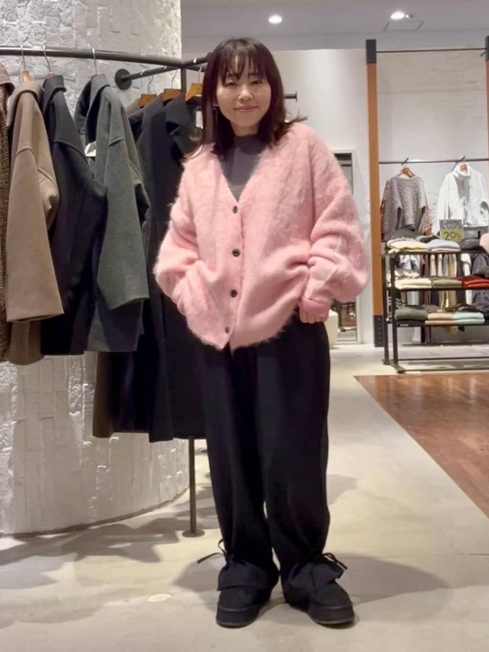 グレー系のニット/セーター、ブラック系のその他パンツ、ピンク系のカーディガン/ボレロを着用したレディースの秋コーディネートの1枚目の写真