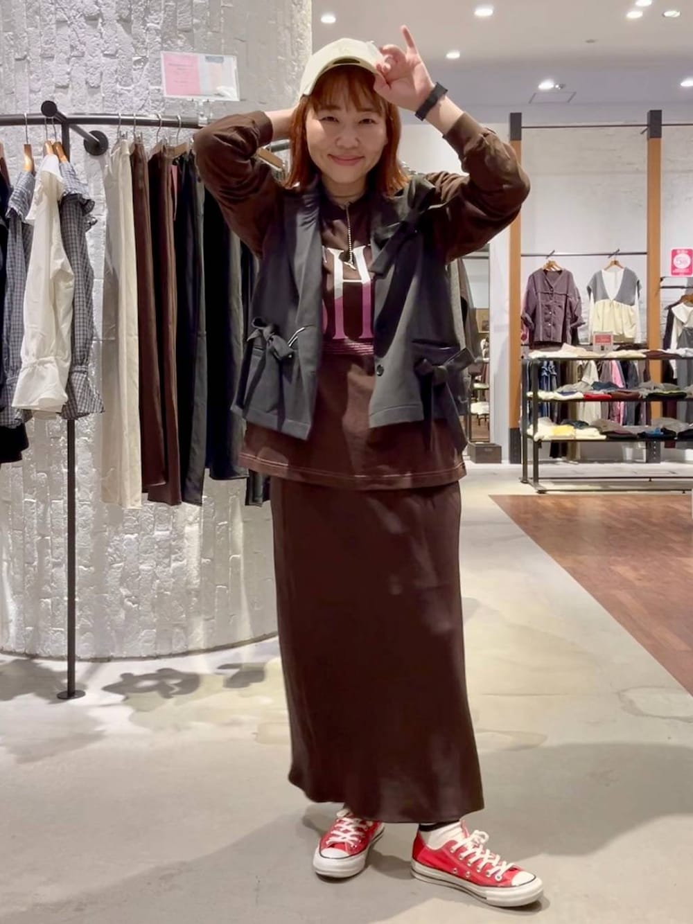 ブラウン系のスカート、ブラウン系のTシャツ/カットソー、レッド系のスニーカーを着用したレディースの秋コーディネートの1枚目の写真