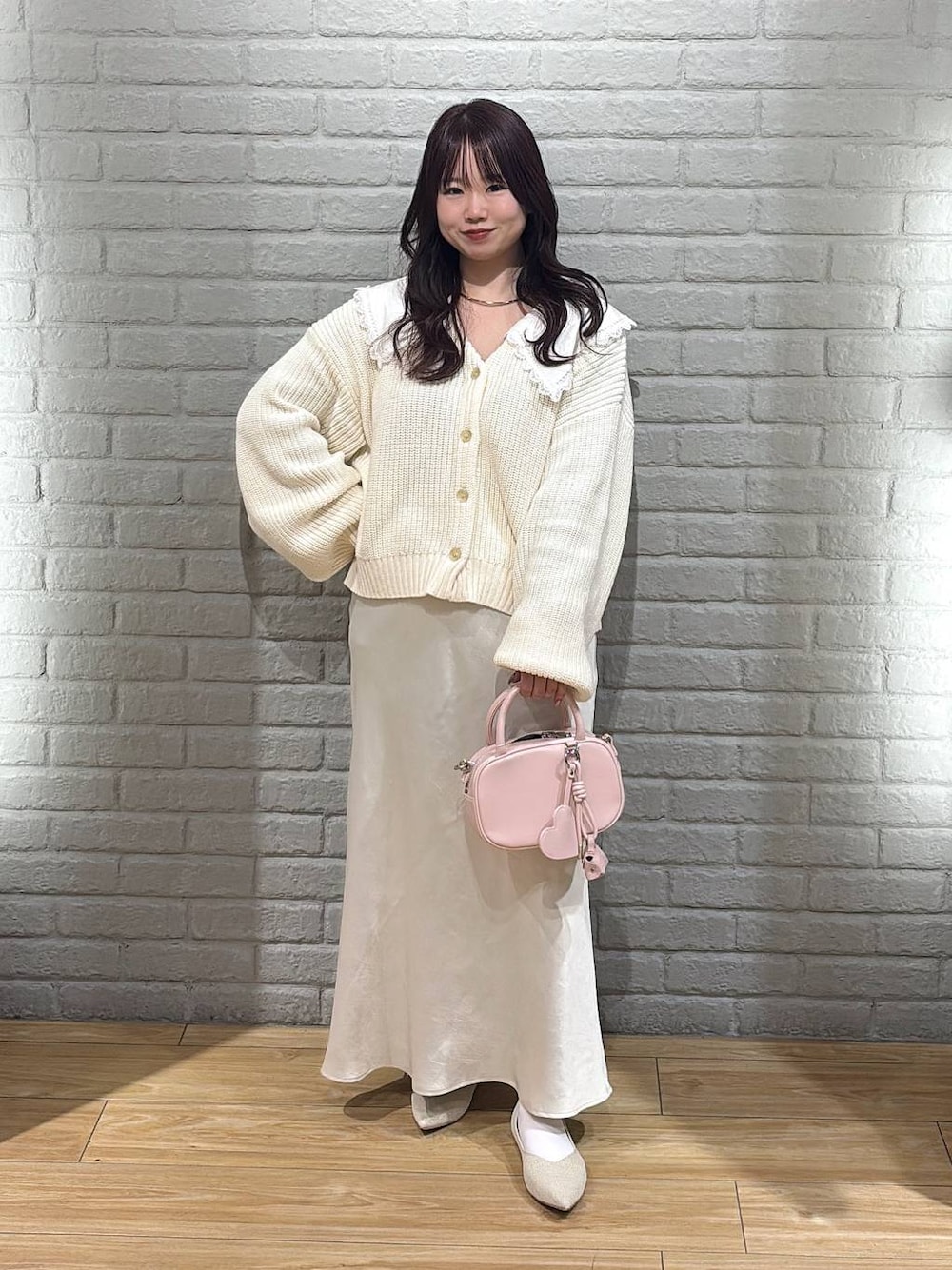 ホワイト系のスカート、ピンク系のボストンバッグ、ホワイト系のパンプスを着用したレディースの冬コーディネートの1枚目の写真